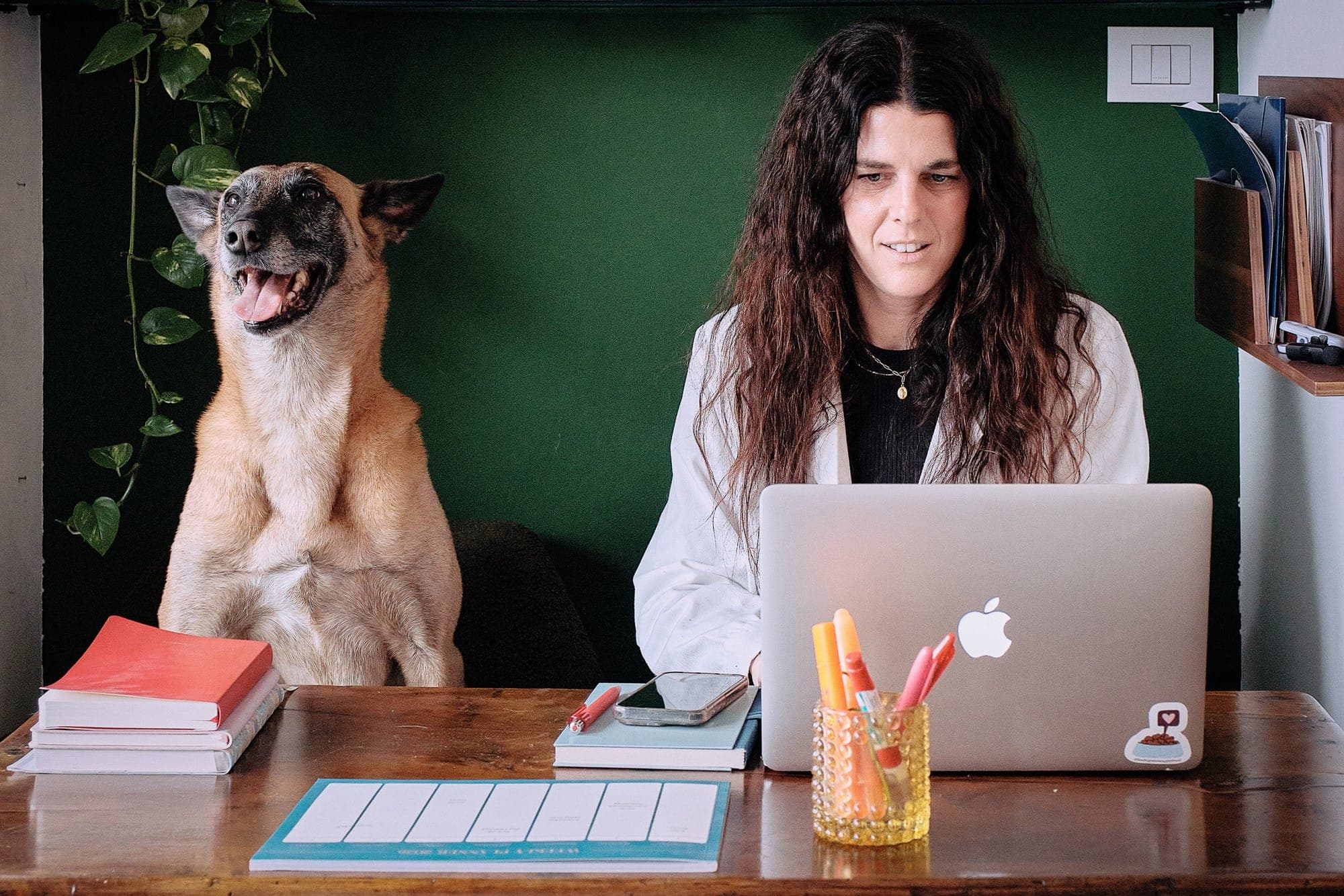 La dott.ssa Alessandra Calini al computer nel suo studio, con un cane seduto accanto alla scrivania