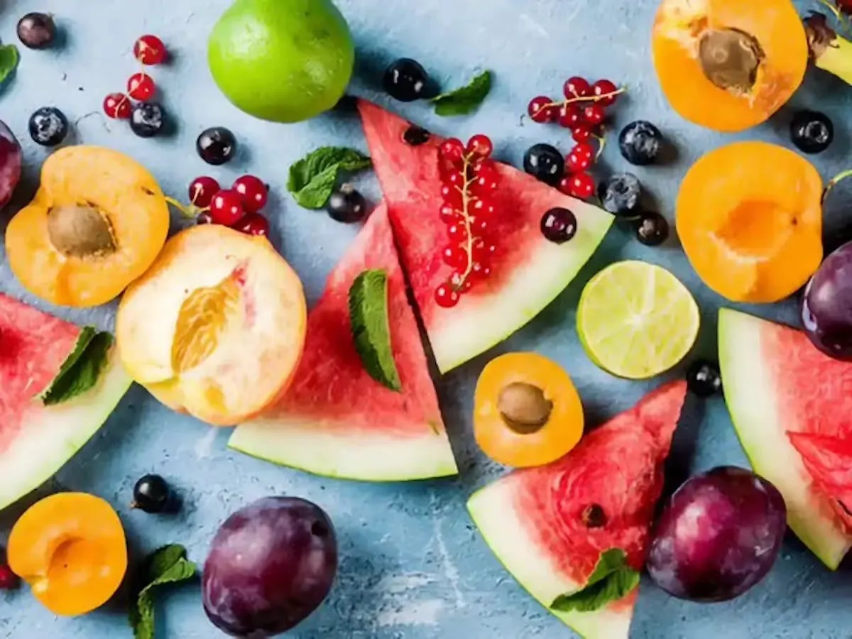 Anguria, albicocche, susine, lime e frutti di bosco tagliati su un fondo azzurro